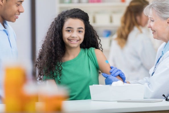 a preteen black girl has bandage over shot with people on either side