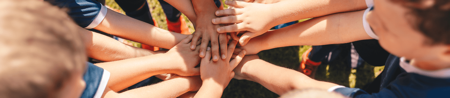 group of children with hands stacked in a circle