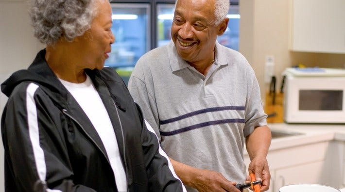 senior couple talk while chopping vegetables at kitchen counter