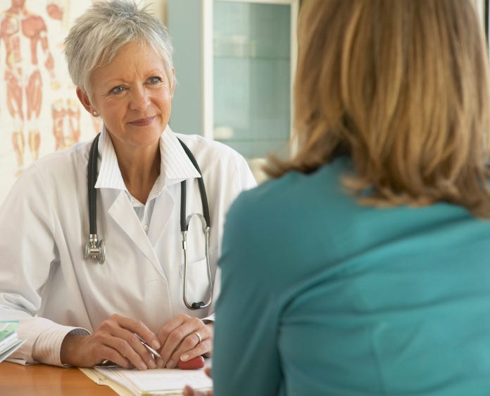 smiling female doctor listens to patient in office