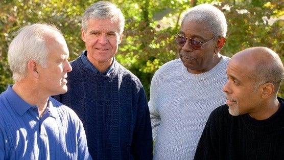 group of middle aged men talking outside