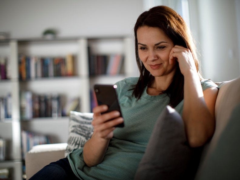 woman sitting on couch looking at phone