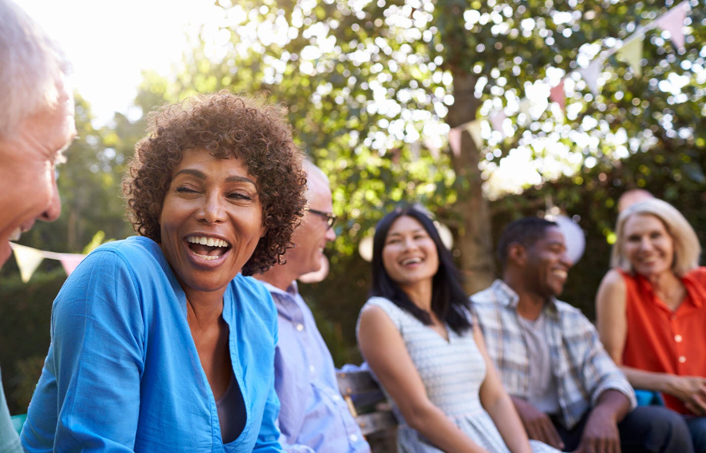 Group of adults sitting on a park bench conversing and laughing