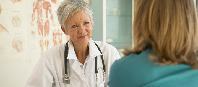 doctor smiles while listening to her patient in exam room