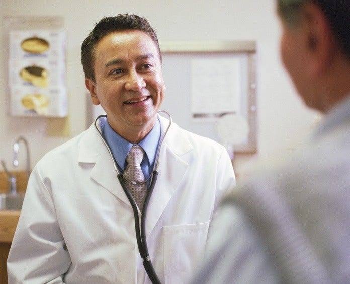 Smiling doctor talking with patient in exam room