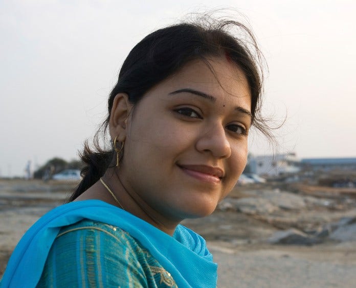 smiling young indian woman in sari standing outside