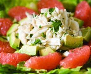 close up of a plate of crab salad with grapefruit and avocado on baby greens