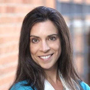 Woman smiling, long, brown hair, teal blazer over a white blouse