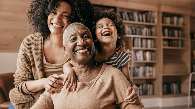 Three generations of smiling family embracing indoors
