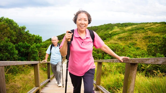 happy senior couple hiking up mountain