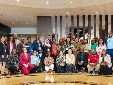 A large group poses in a hotel lobby or conference space for a formal group photo.