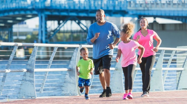 young family walks for exercise together along a river