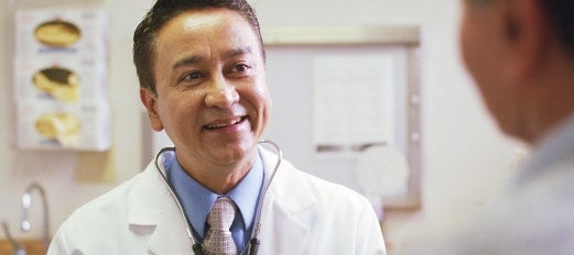 smiling doctor talks with patient in office settting