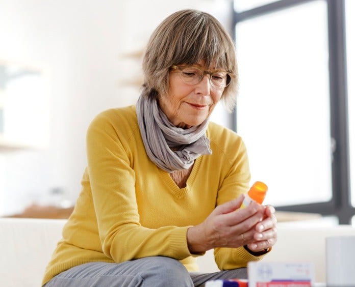 senior woman reading a pill bottle at home