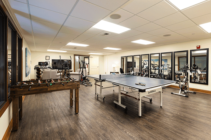 Recreation room with ping pong table, foosball, and exercise equipment.