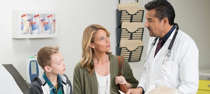 a male teen and his mother listen to their doctor in exam room