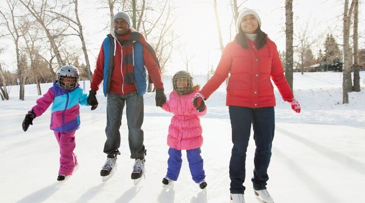 parents with two young children skate on outside rink