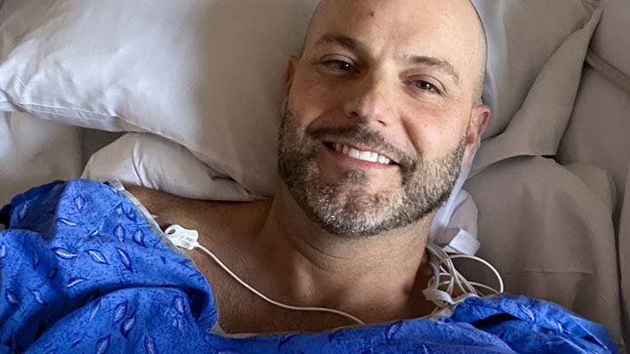Hombre sonriente descansando en una cama de hospital.