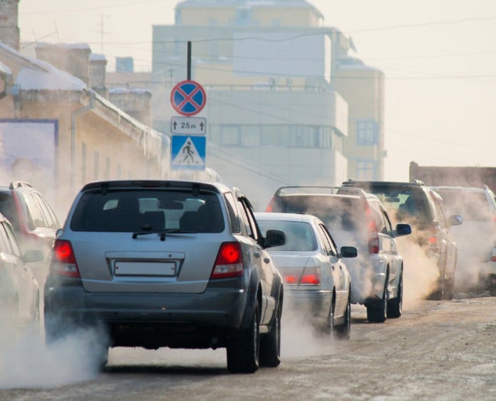 traffic jam on city streets with exhaust fumes coming from cars