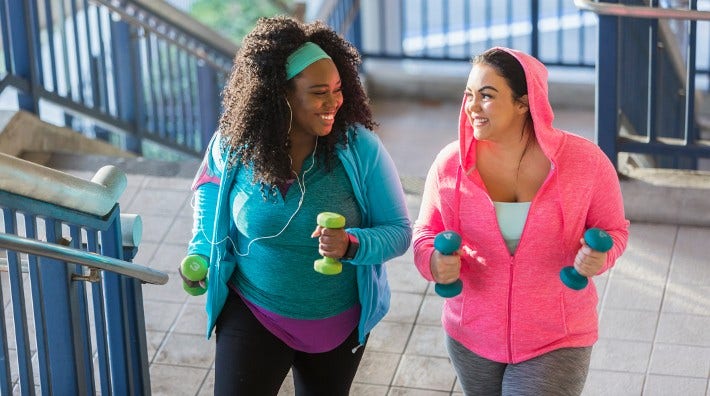 two women walking up stairs holding hand weights