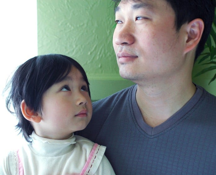 little girl sitting in her father's lap and looking up at him