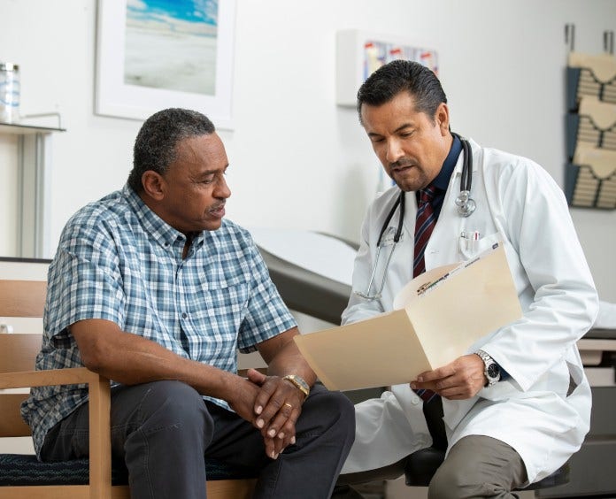 doctor discussing a patient's chart with him in exam room