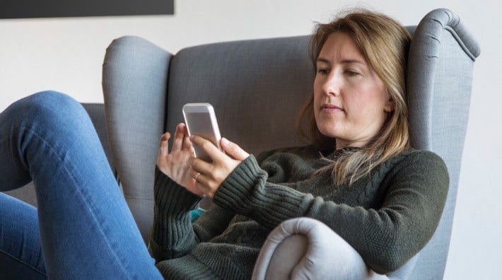 young woman sitting in a chair looking at her cell phone