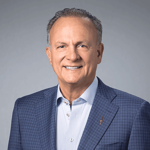 Smiling man in blue checkered blazer and light shirt.