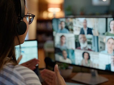 A person attending a webinar with people on monitor