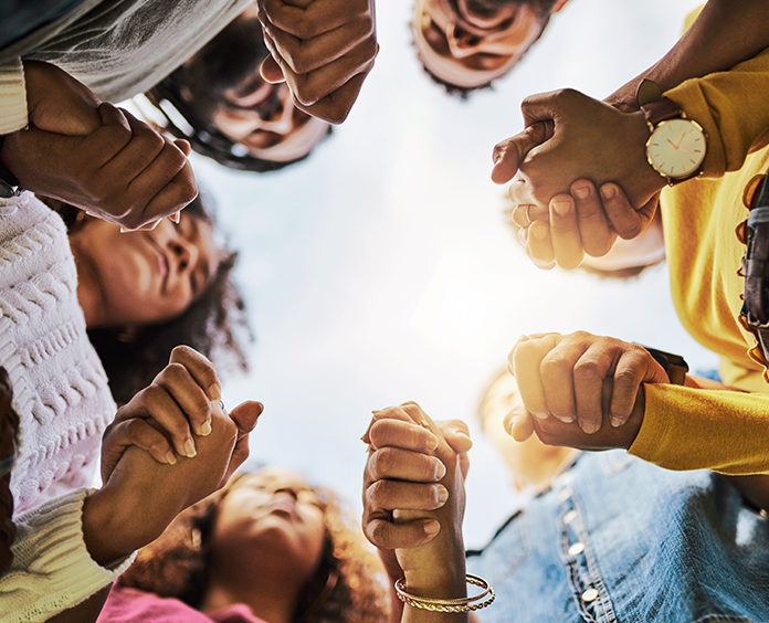 group of young black adults holding hands in a circle