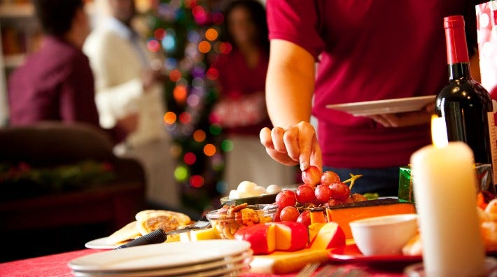 woman chooses grapes at holiday buffet