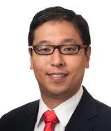 Asian man wearing rectangular black glasses in black suit jacket, white shirt, and red tie. 