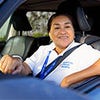Persona sonriente sentada en un automóvil con uniforme de trabajo.