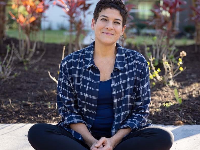 A woman sitting with her legs crossed on the sidewalk 