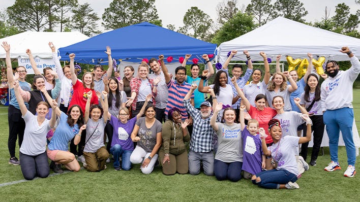 Gran grupo celebrando juntos bajo carpas de evento al aire libre.