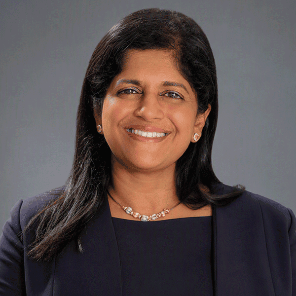 Smiling woman wearing a dark blazer and colorful necklace.