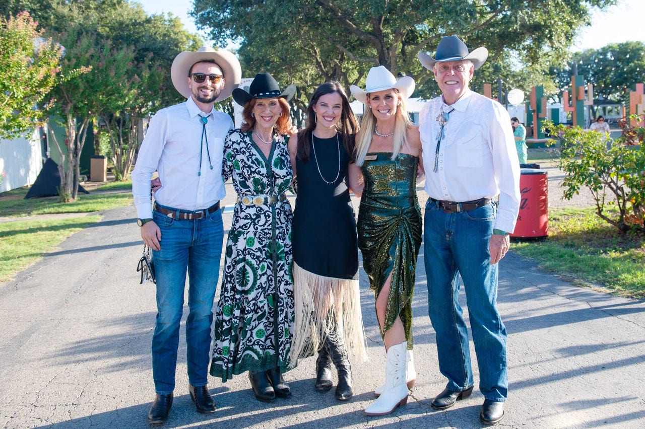 Five people in cowboy hats posing together outdoors.
