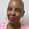 Mujer sonriente con aretes de aro y blusa rosa.