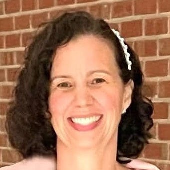 Headshot of researcher, Karen Murphy, PhD, short, dark, curly hair, white hairpin, blue top under a pink shawl