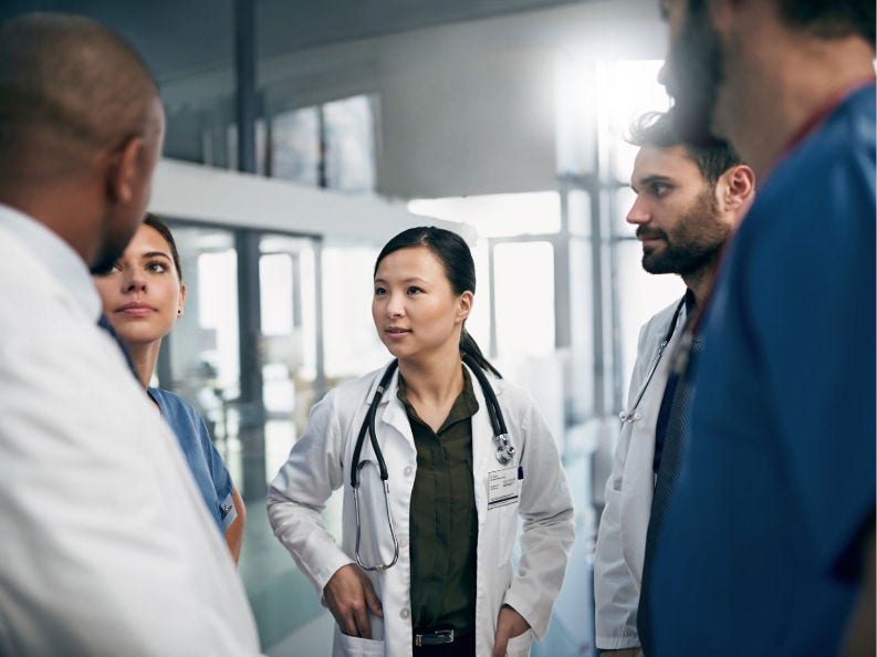 Five doctors talking in a hallway