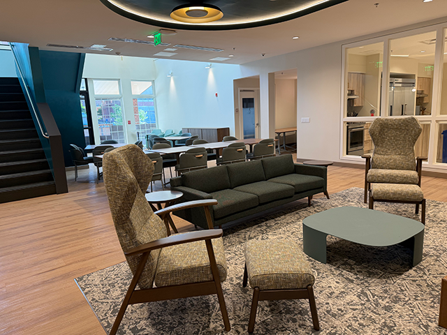 Modern lounge with armchairs, sofa, staircase, and open seating area.