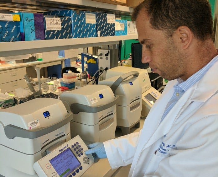 Dr. Andras Heczey checks the settings of his “molecular copier,” a PCR machine, which copies, or amplifies, DNA segments.