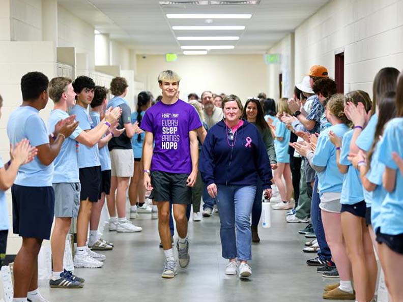 Students clapping for people walking down a hallway for an event