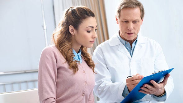 Woman looks at document with doctor