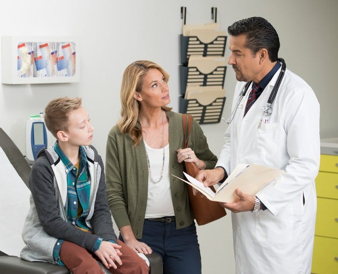 a male teen and his mother listen to their doctor in exam room