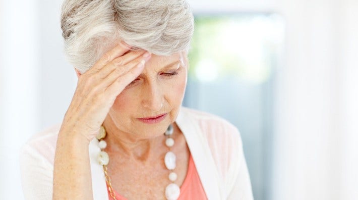 worried senior woman rubs her forehead