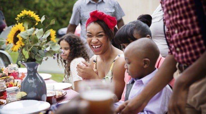 large family eats around picnic table outdoors