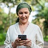 white woman wearing green head wrap looking down at her cell phone