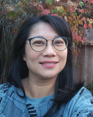 Photo of Rita Shiau, MPH, blue sweater with geometric pattern, long black hair, black eyeglasses