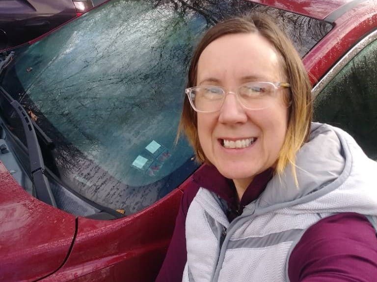 white woman standing in front of red car